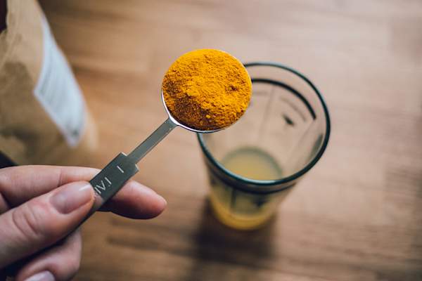 Raw tumeric powder in measuring cup