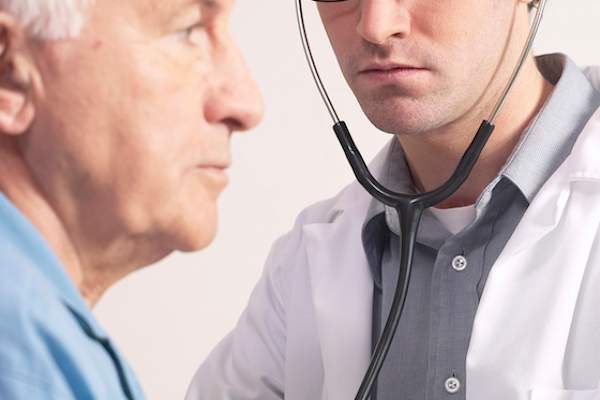 医生用听诊器听老人的心脏。