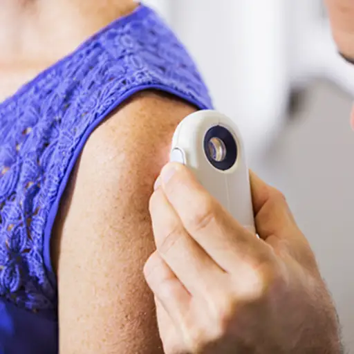 Dermatologist looking at lesion on woman's arm.