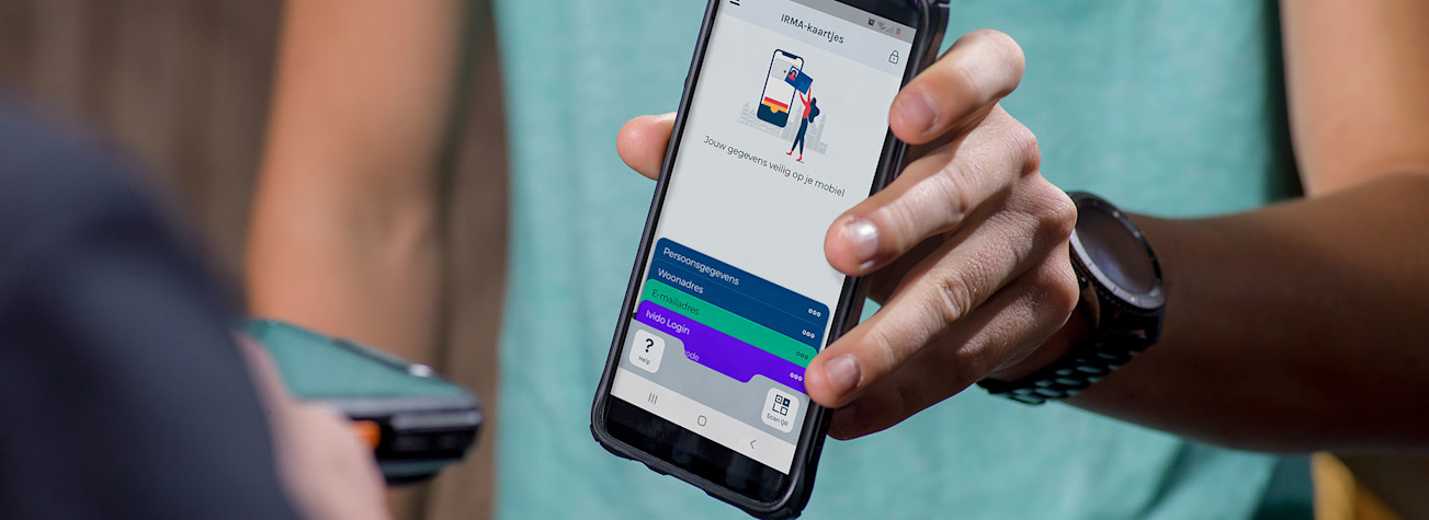 Close-up van smartphone in iemands hand waarop de IRMA-app te zien is.