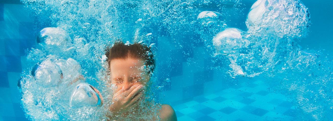 Little boy under water pinching his nose