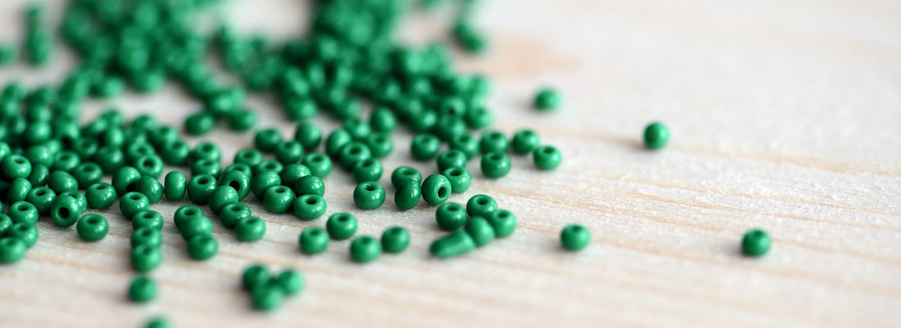 Closeup of green beads scattered on a wooden surface