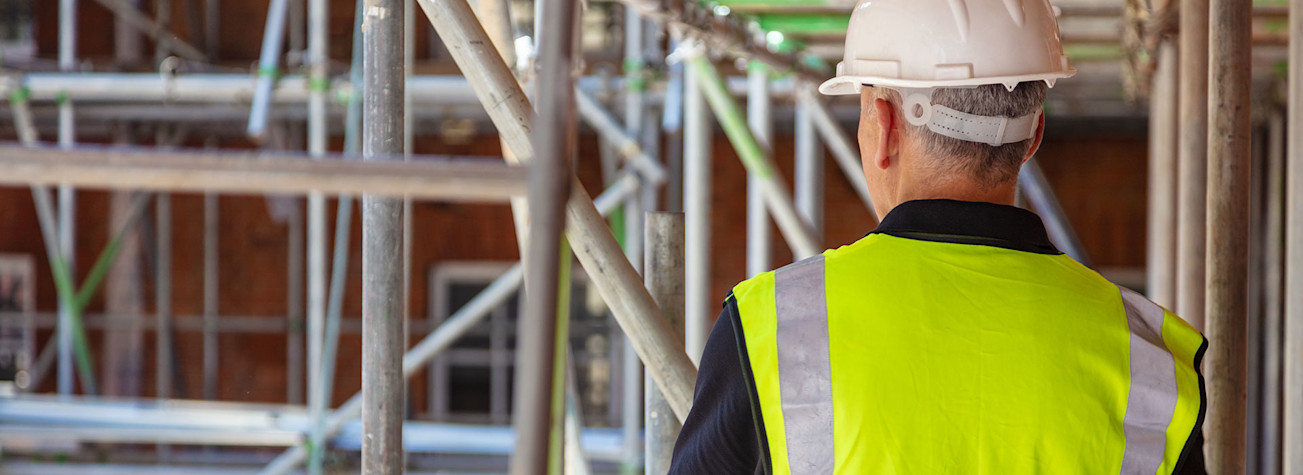 Rear view of a construction worker wearing a safety vest and helmet on a construction site