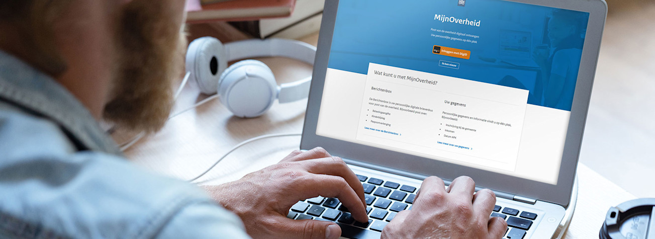 Man achter een laptop waarop op het scherm de website mijn.overheid.nl te zien is.
