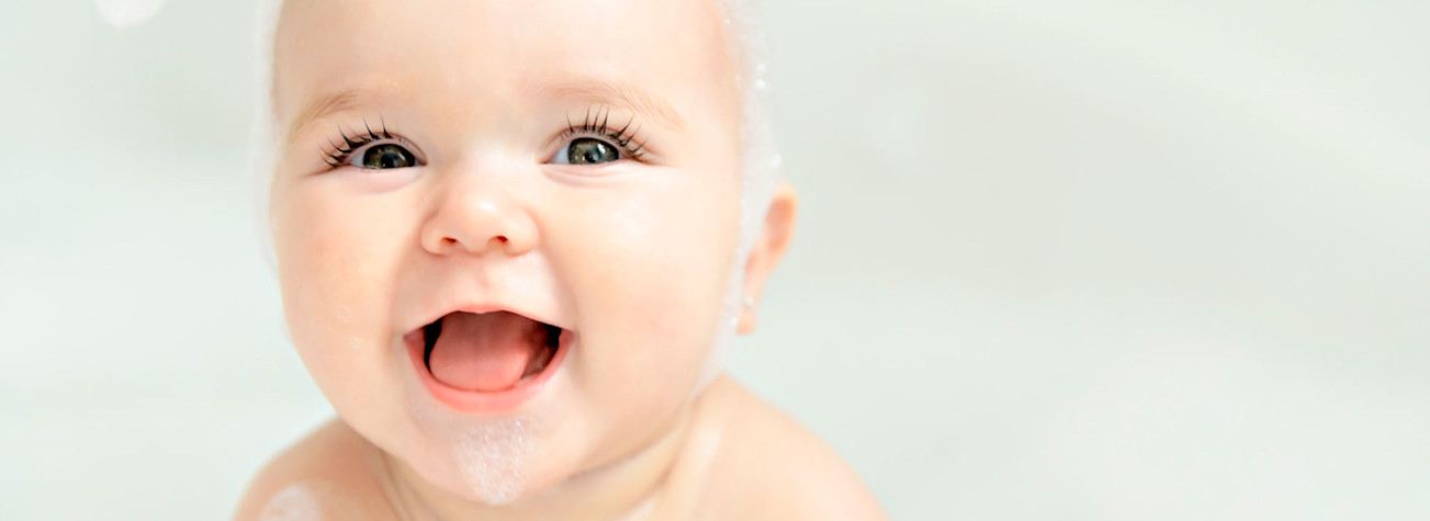 Baby girl bathes in a bath with foam and soap bubbles