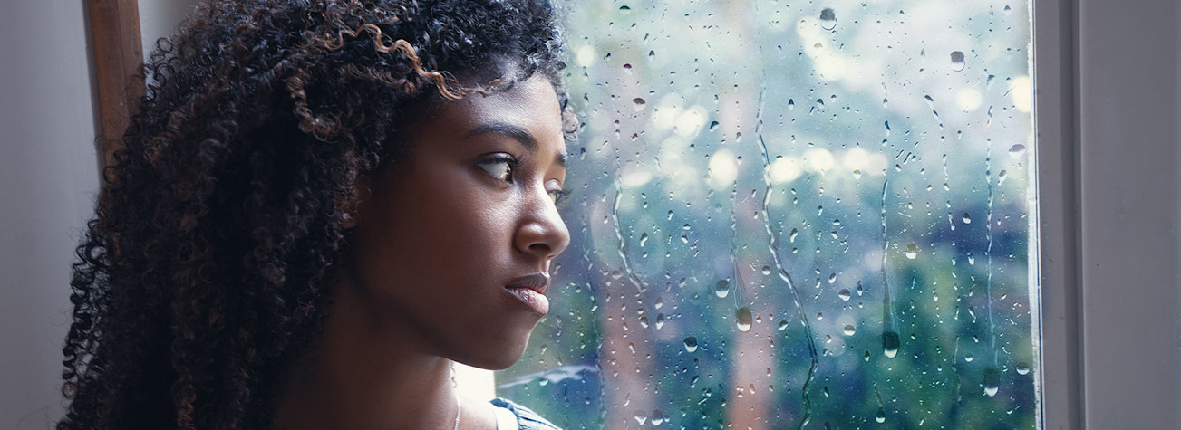 Sad young woman stares out of a window