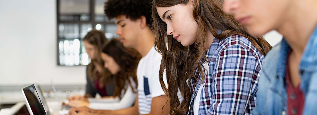 Group of high school students using laptop in classroom