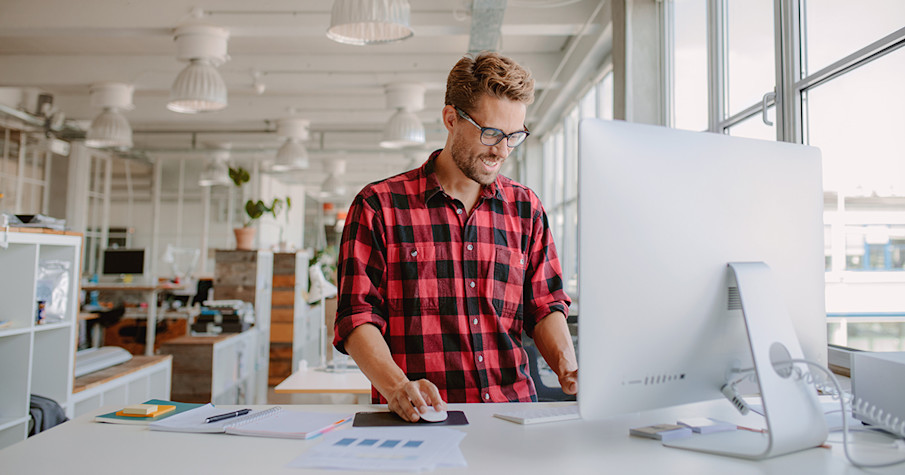 Young man standing working behind a pc