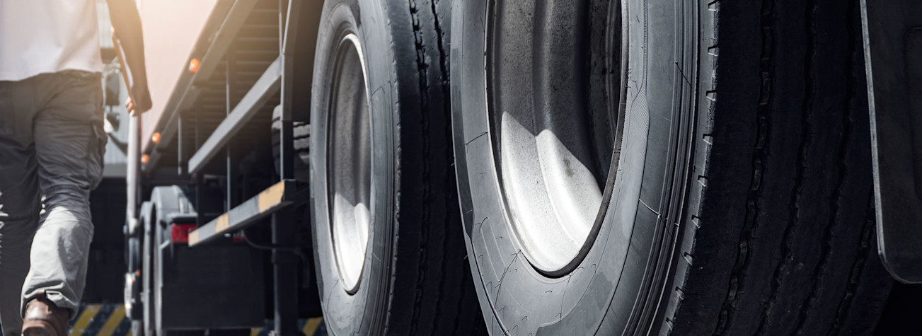 Close-up of truck wheels and a truck driver holding clipboard