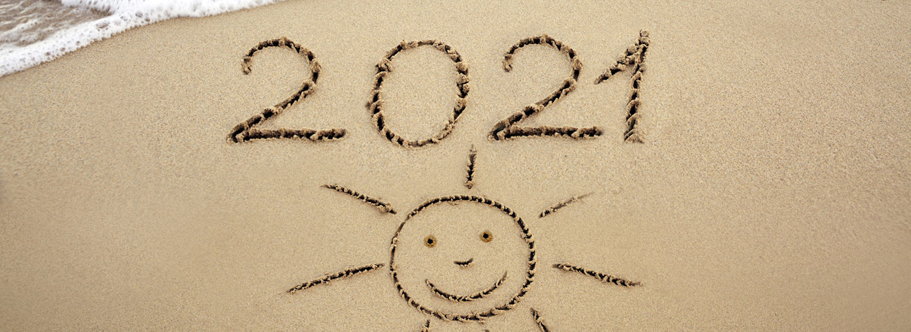 The year 2021 and a drawing of the sun in the sand on the beach