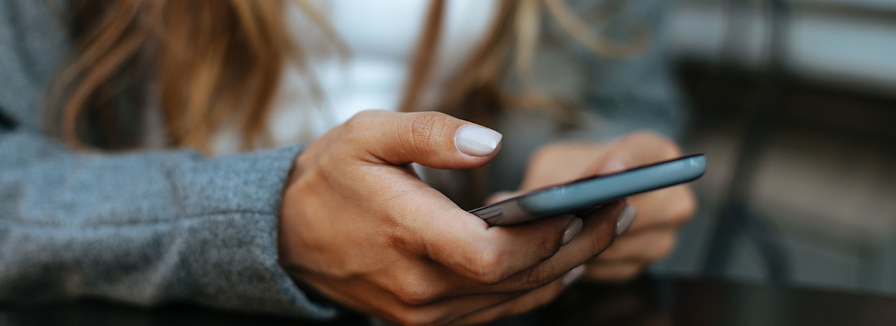 Close-up of a woman in grey coat using a smartphone