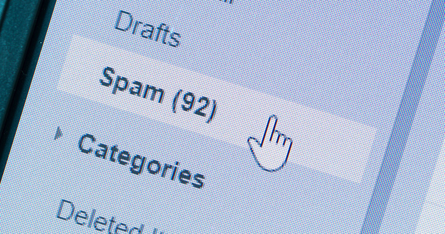 Close-up of a monitor with a mouse pointer hovering over the spam folder in a mailbox.