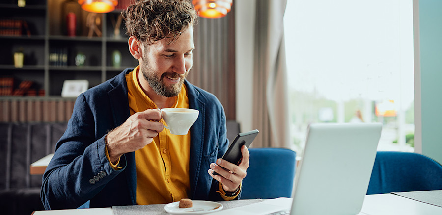 jonge zakenman werkt in een café op zijn laptop en belt met zijn telefoon