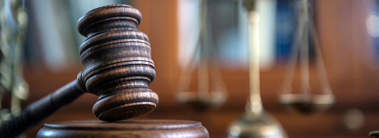 Close-up of a gavel with a scale in the background.