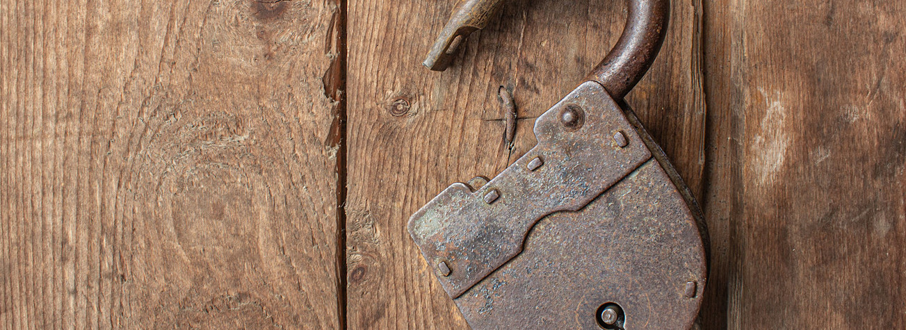 Old rusty opened padlock without a key hanging on a wooden door