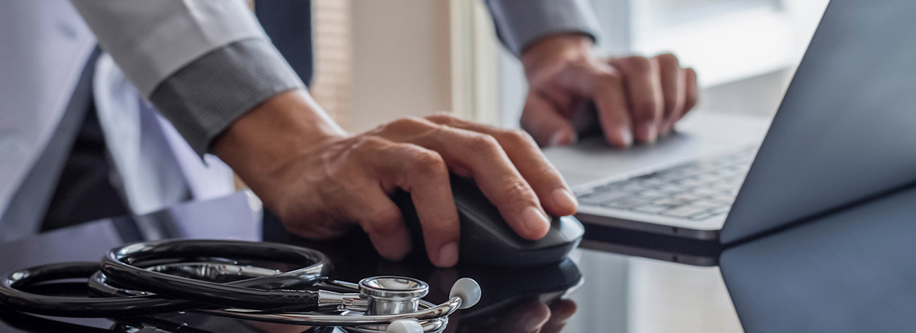 Male doctor looking up patient data on a laptop