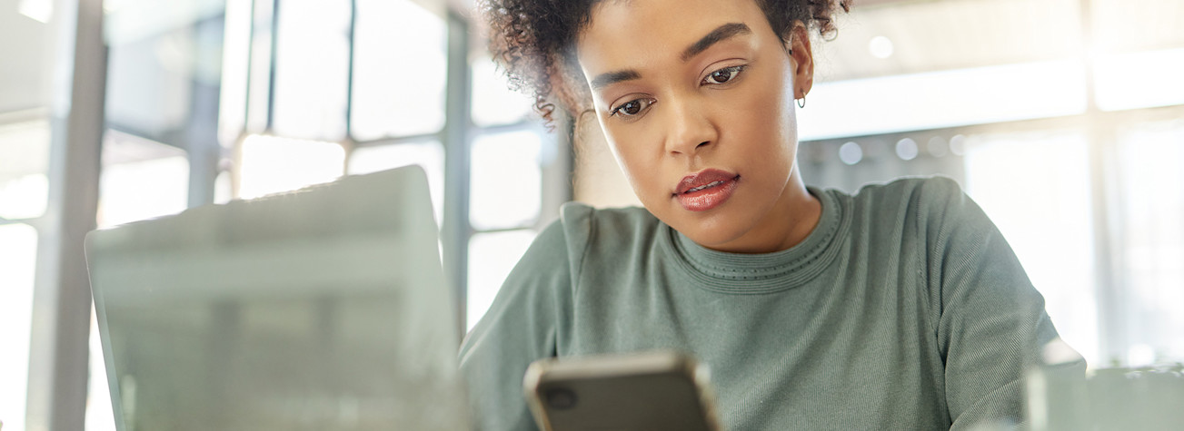 Lady logs in with mobile on laptop