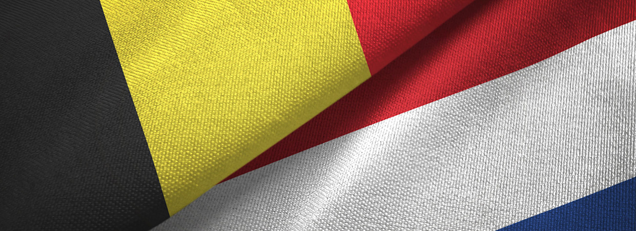 Close-up of the fabric of a Dutch and Belgian flag lying next to each other