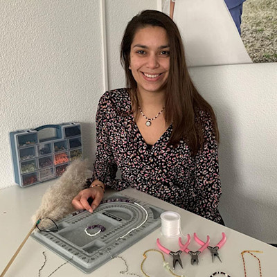 Reena Bateswar-Harpal behind a table with materials and tools to make beaded bracelets