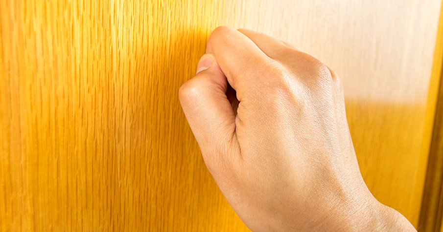 Close-up of a hand knocking on a door