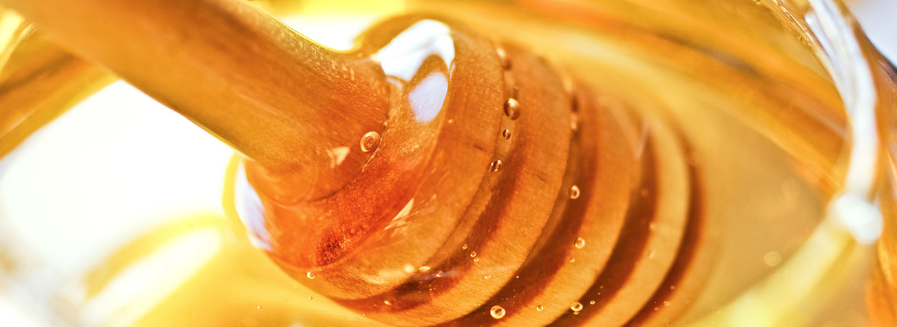 Close-up of a honey jar with a wooden honey spoon