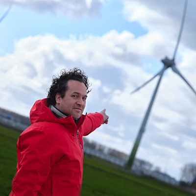 Paul de Ridder van Particibeter, wijzend naar een windmolen