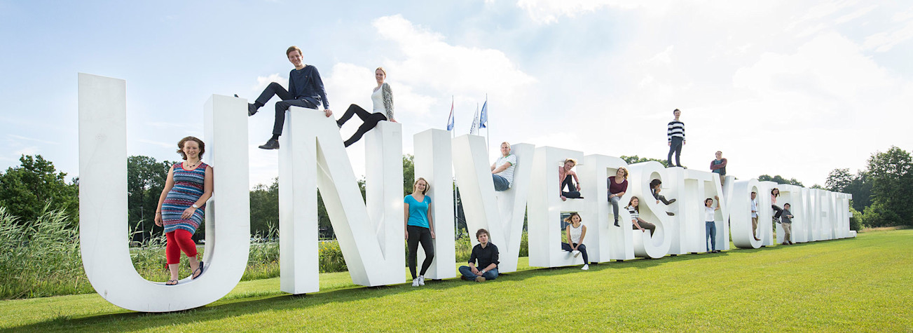 Levensgrote letters op de campus van de Universiteit Twente die de (Engelse) naam van de universiteit, University of Twente, weergeven.