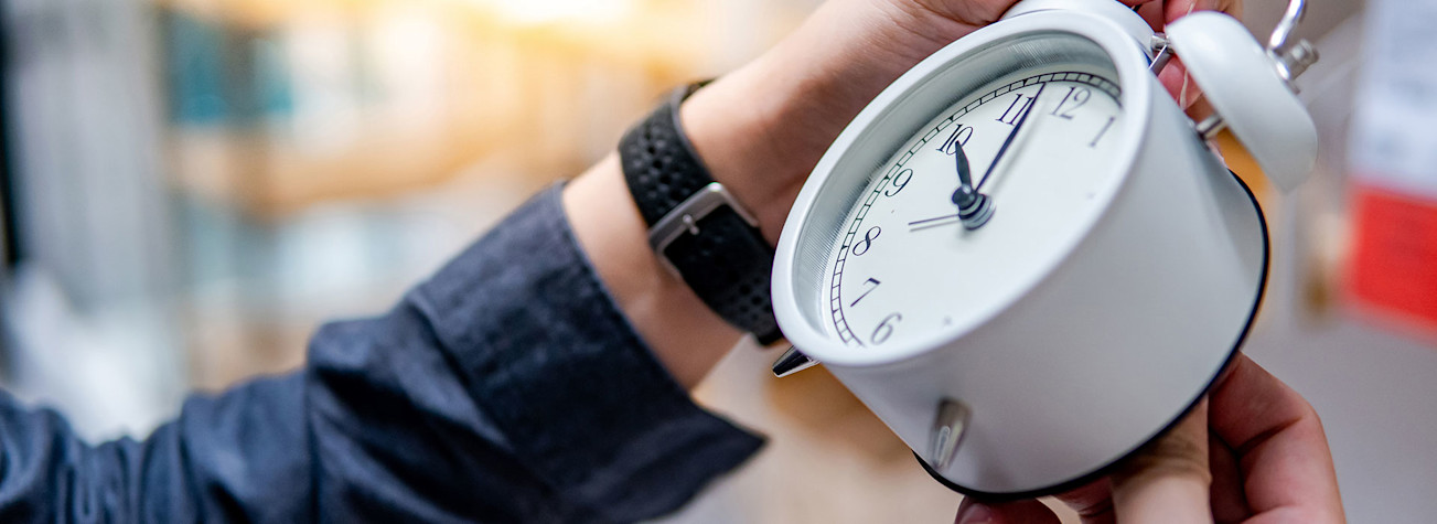 Male hand adjusts the time on a white alarm clock