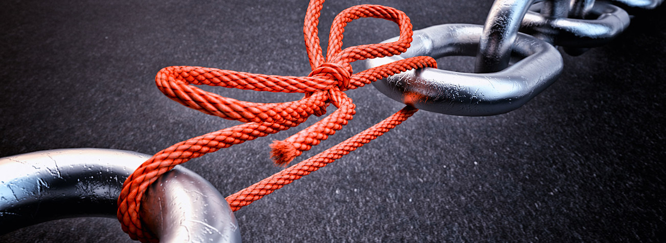 Metalen ketting verbonden door een rood geknoopt touw op zwarte achtergrond