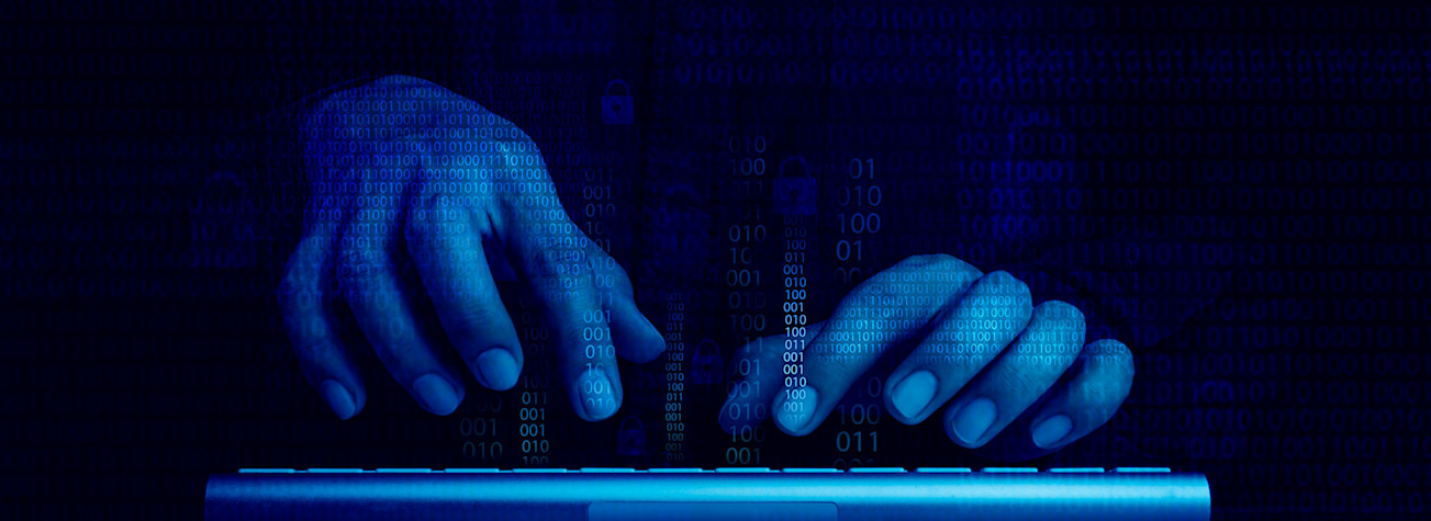 Blue-lit hands work on a keyboard in a dark room