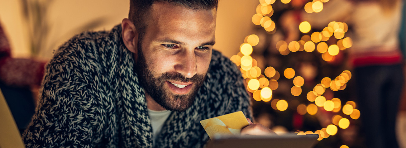 Man with credit card in hand does Christmas shopping on a tablet