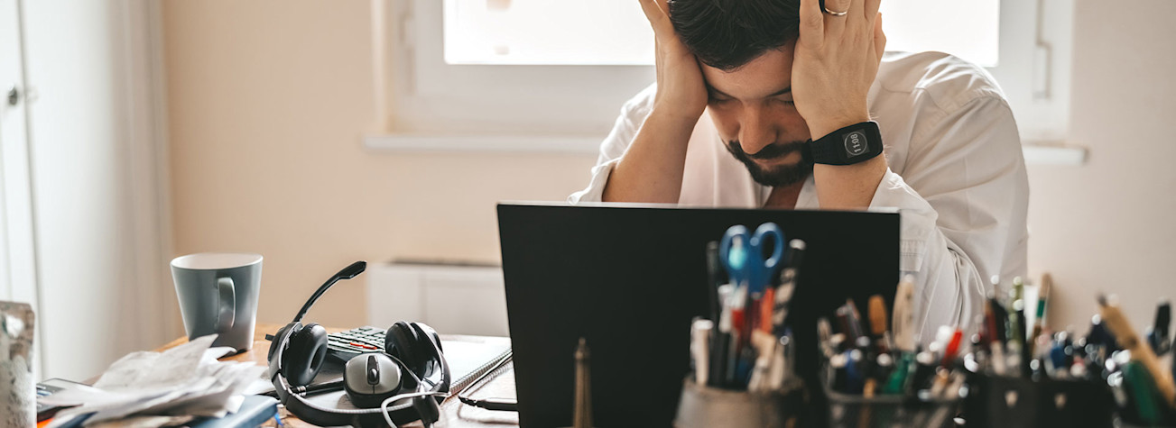 Vermoeide, gefrustreerde, uitgeputte werknemer achter zijn bureau 