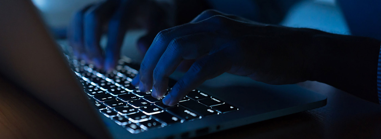 Close-up of someone working on a laptop in a dark room