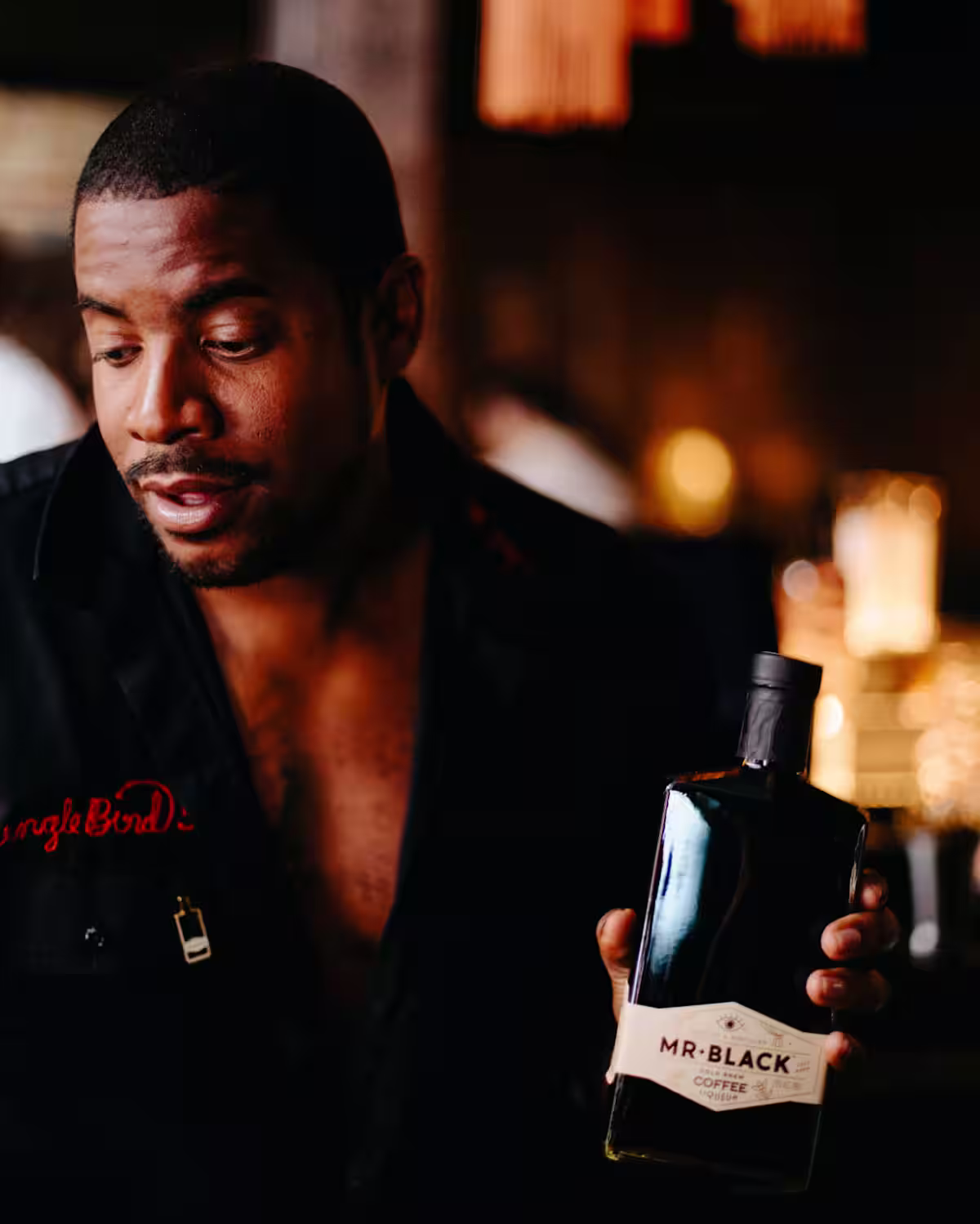 A focused bartender with a bottle of Mr Black Coffee Liqueur in his hand