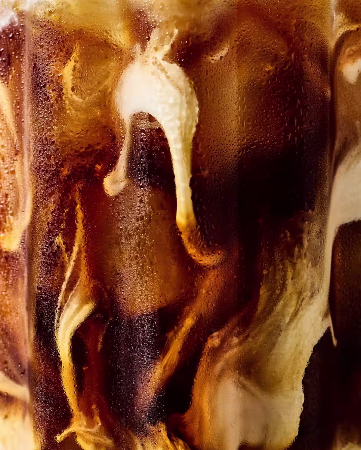 Milk being poured into an iced coffee latte cocktail