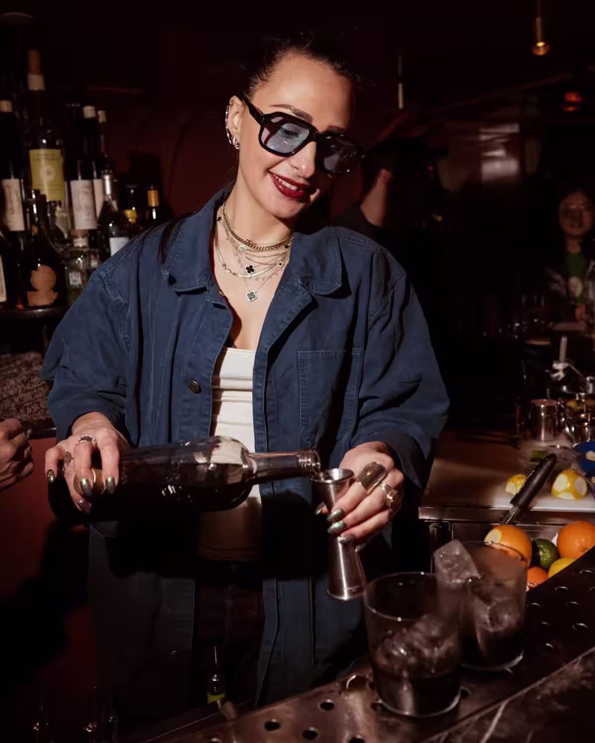 A bartender pouring coffee liqueur into a jigger