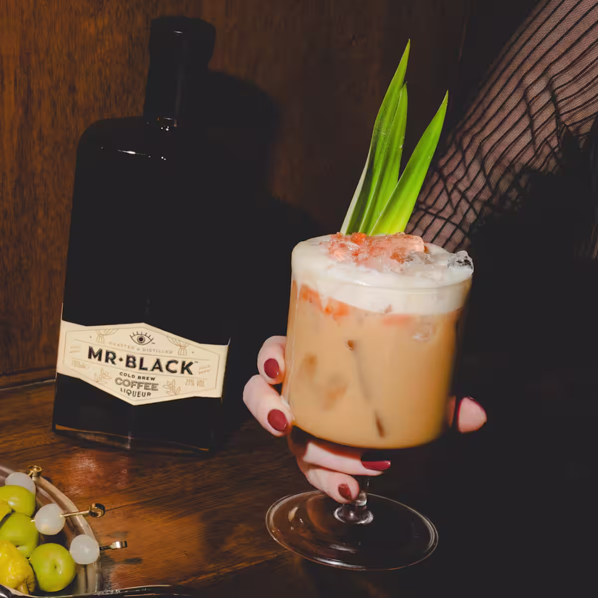 A Café Colada cocktail with a bottle of Mr Black Coffee Liqueur.