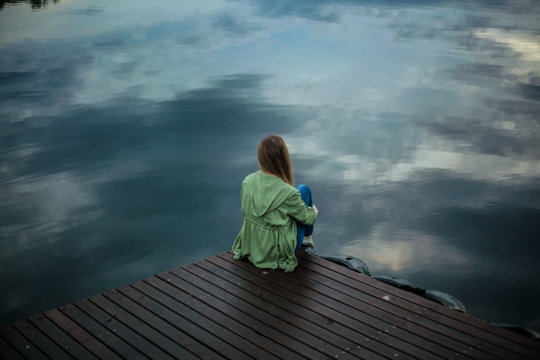 woman-sitting-pier-water-gloomy.jpg