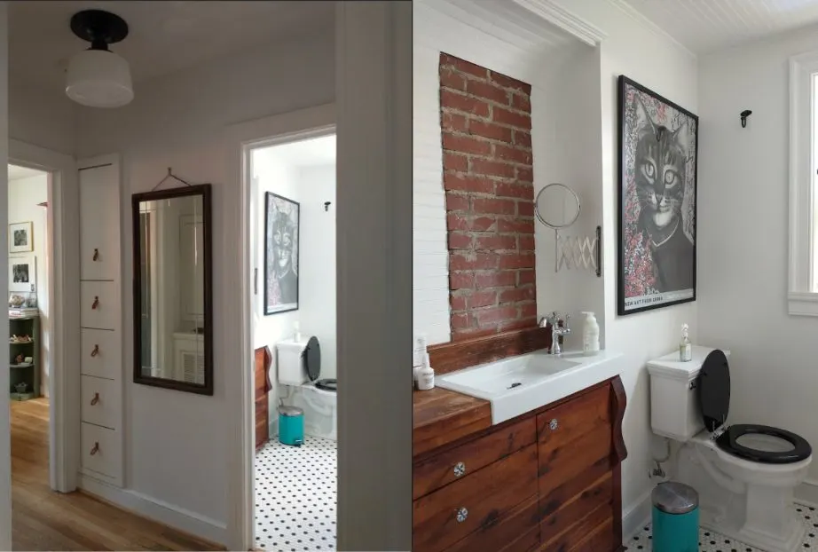 Bathroom with a wood vanity, an exposed brick wall, framed art, and a mirror reflecting the hallway.
