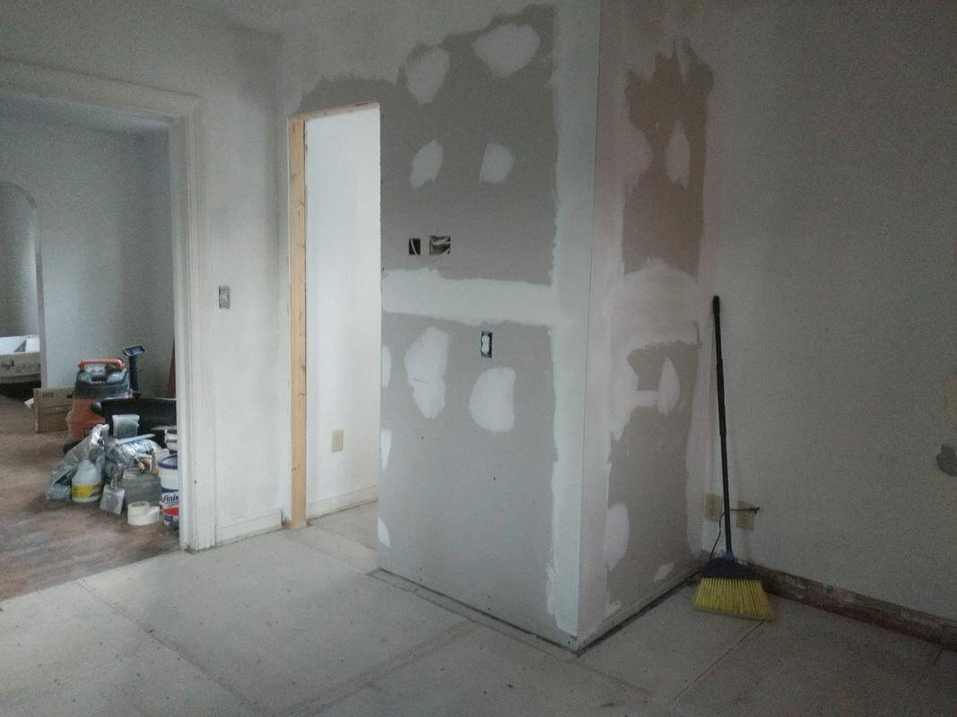 View of the half bath with fresh drywall as seen from the kitchen