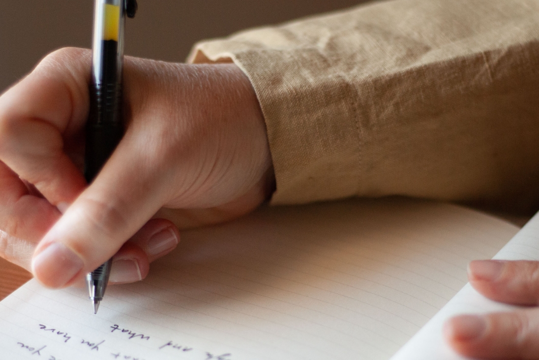 A hand writing with a pen in a notebook