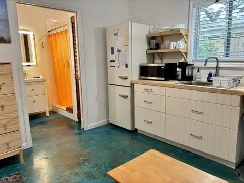 Kitchenette and bathroom entry with a retro refrigerator, microwave, butcher-block counter, and blue-stained floor.
