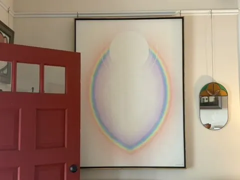 Entry with a red front door, a large luminous abstract painting, and an oval mirror.