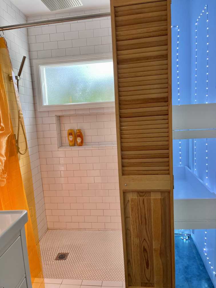 Jekyll Island Airbnb - modern, beachy bathroom with neon lights and bright orange shower curtain.