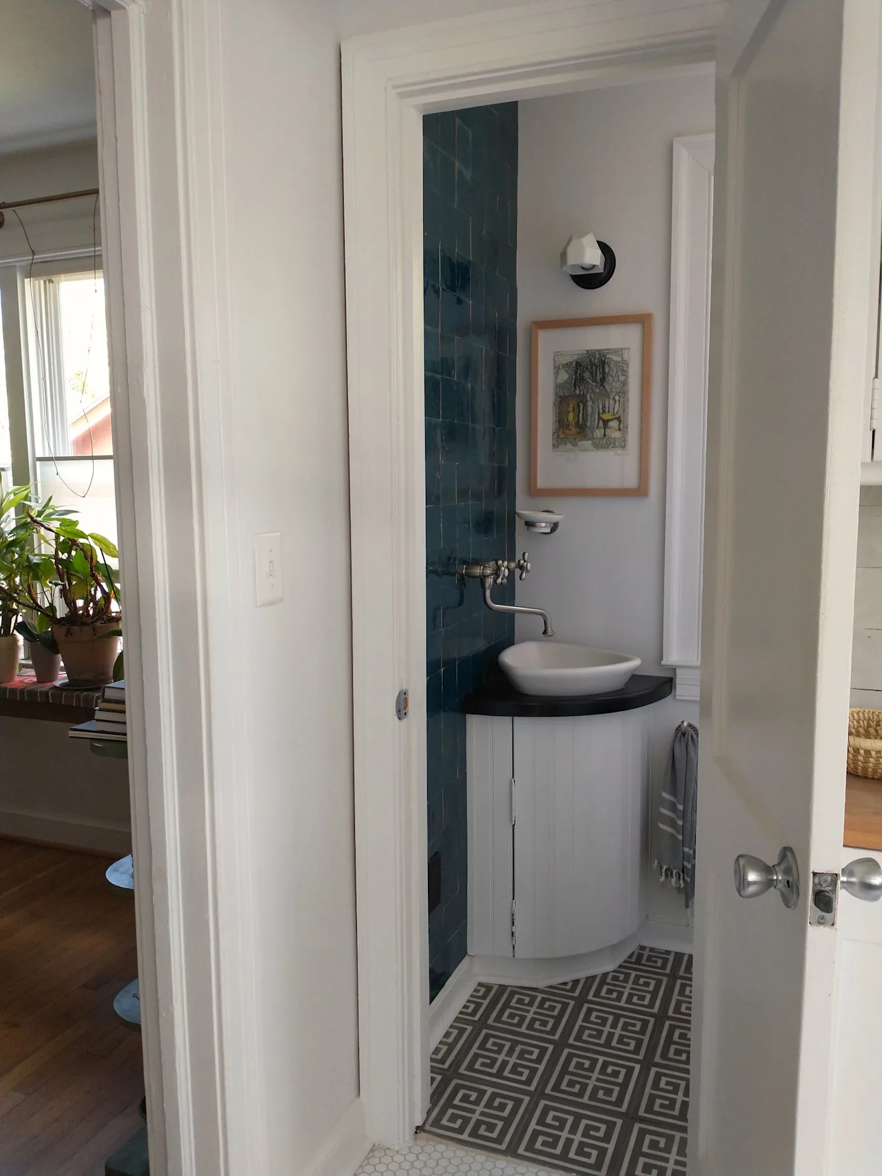 View through a doorway to a compact bathroom with a vessel sink and a geometric tile floor.