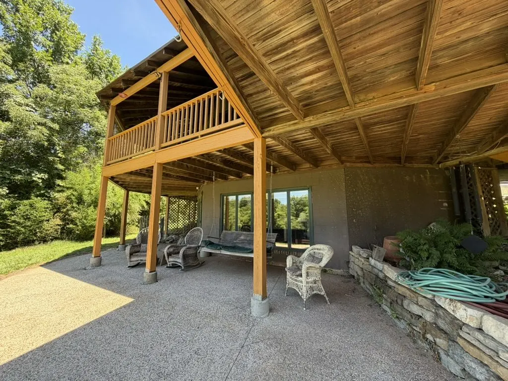 Exterior view of the dome home's two-level wraparound deck and stone patio with landscaped grounds.