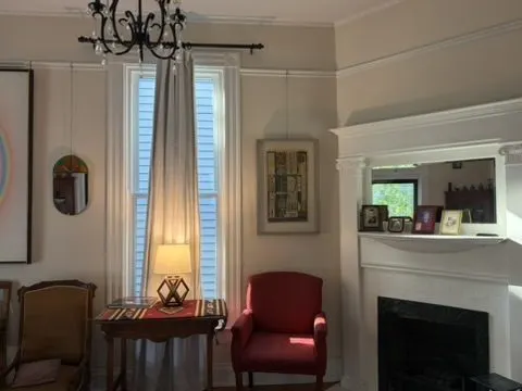 Sitting room with a marble fireplace, a red accent chair, a floor lamp, and picture-rail molding.