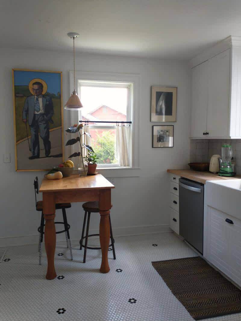 A breakfast nook with art, wooden countertops, and a farmhouse sink.