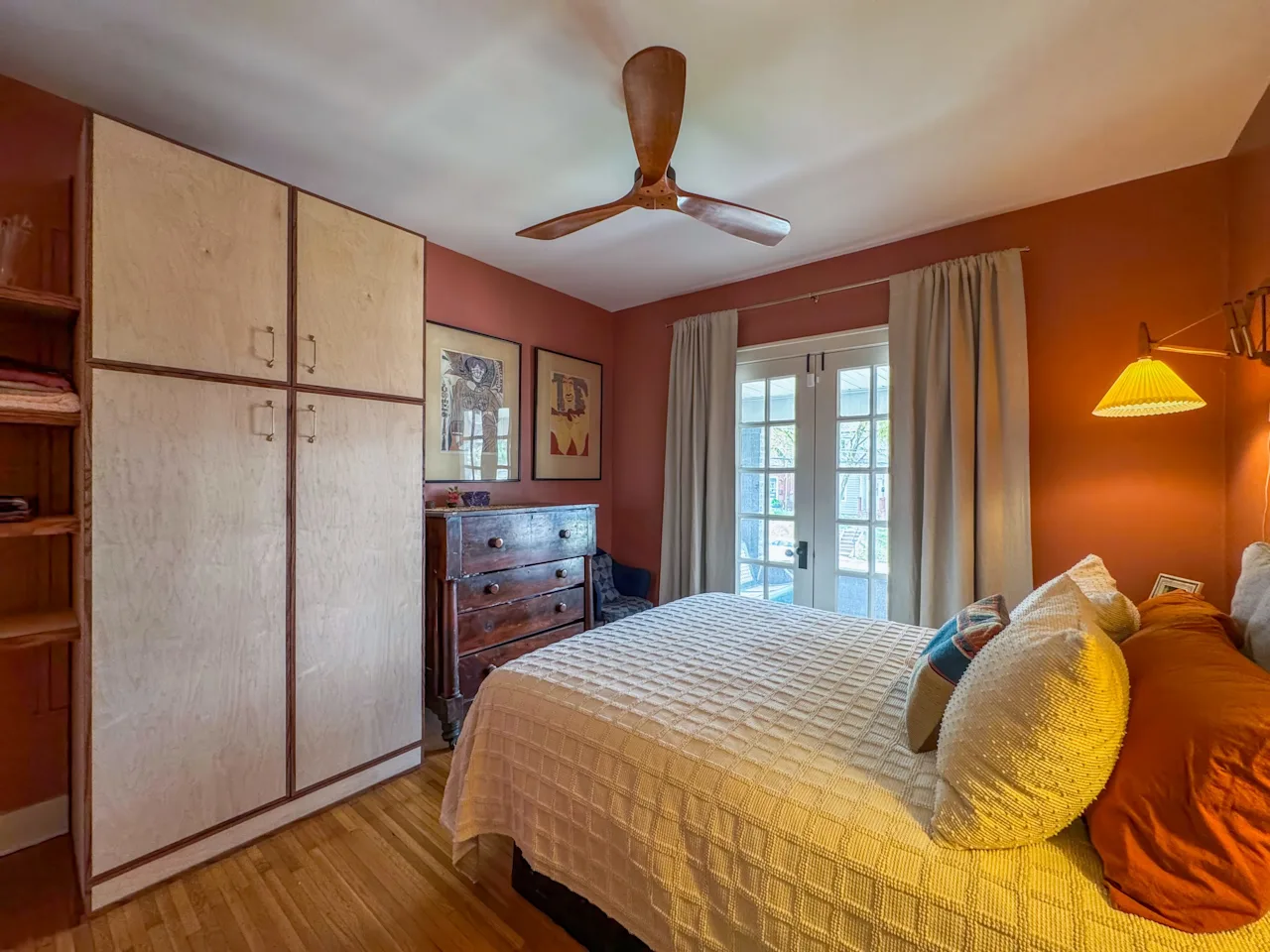 Bedroom with a custom birch-plywood built-in wardrobe, a ceiling fan, and a terracotta accent wall.