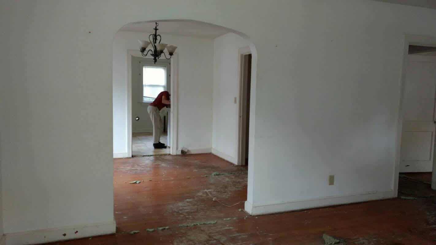 The living room after removing the carpet, revealing beautiful hardwood floors